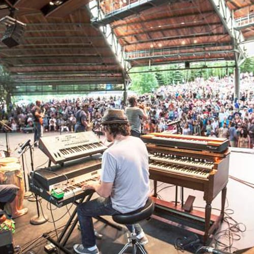 Musician performing at outdoor concert with crowd.